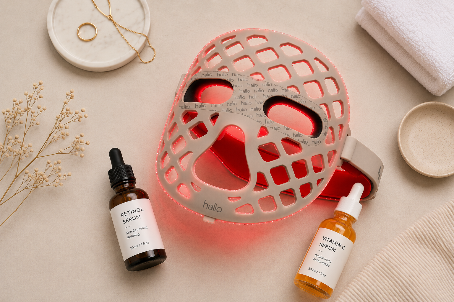 Flat lay of an LED face mask alongside retinol serum and vitamin C serum bottles, illustrating skincare device and active ingredient pairing
