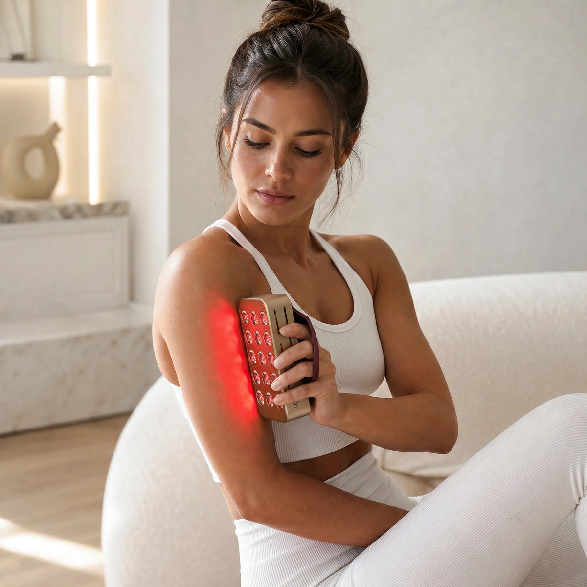 Woman holding the Halio RegenBoost red light panel against her upper arm.
