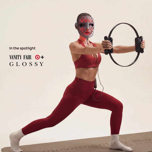 Woman wearing a red LED face mask and holding a circular device; banner text reads “In the spotlight Vanity Fair O+ Glossy.”